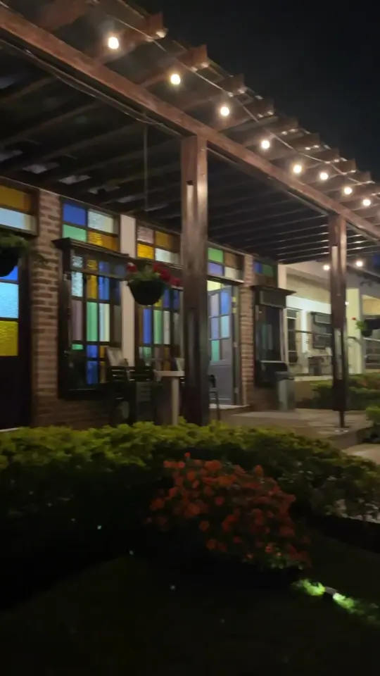 Pérgola con luces cálidas junto a los vitrales de la finca
