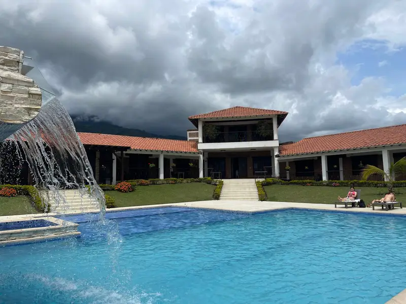 Piscina con cascada y la casa principal de Sunrise Calima a plena luz del día